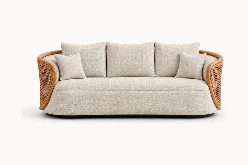 A modern curved three-seater sofa with a light beige textured fabric upholstery, natural woven rattan armrests, and four matching throw pillows, shown against a plain white background.