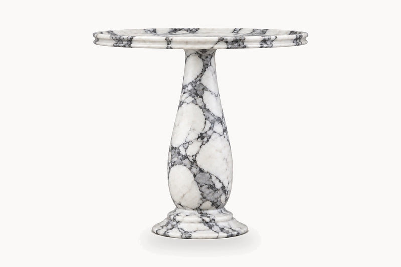 A round pedestal table made of white marble with prominent gray and black veining, shown against a plain white background.